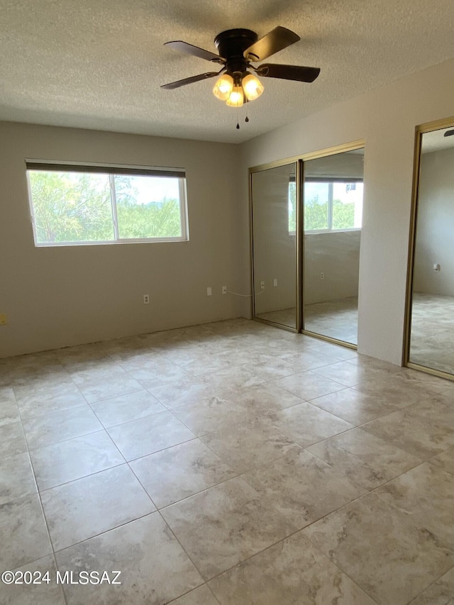 unfurnished bedroom with ceiling fan and a textured ceiling