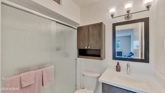 bathroom featuring toilet, an enclosed shower, and vanity