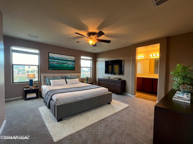 bedroom featuring ensuite bathroom, light colored carpet, and ceiling fan