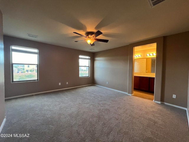 unfurnished bedroom featuring ensuite bathroom, light carpet, and ceiling fan