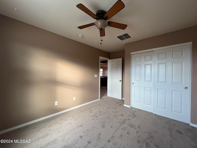 unfurnished bedroom featuring light carpet, a closet, and ceiling fan