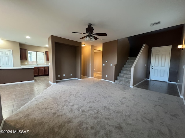 unfurnished living room with light tile patterned flooring, visible vents, a ceiling fan, and baseboards