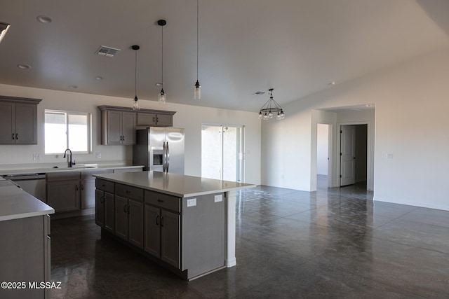 kitchen featuring pendant lighting, sink, lofted ceiling, appliances with stainless steel finishes, and a center island