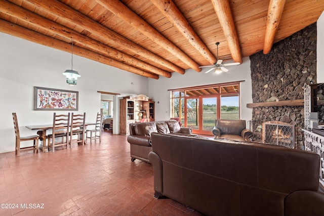 living room with a towering ceiling, a stone fireplace, ceiling fan, wooden ceiling, and beam ceiling