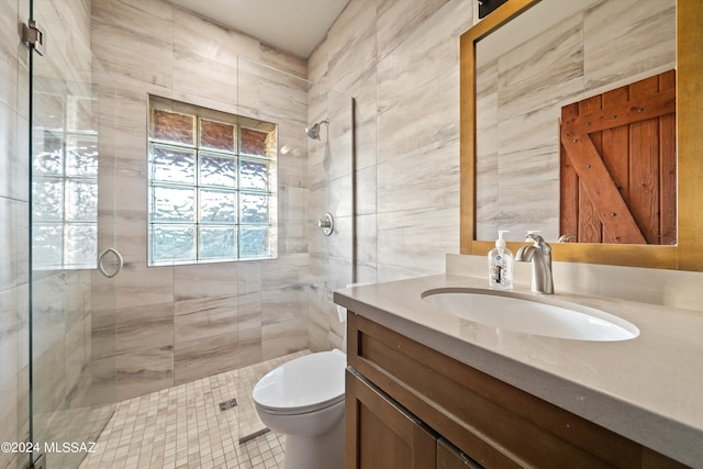 bathroom featuring vanity, toilet, tile walls, and a tile shower