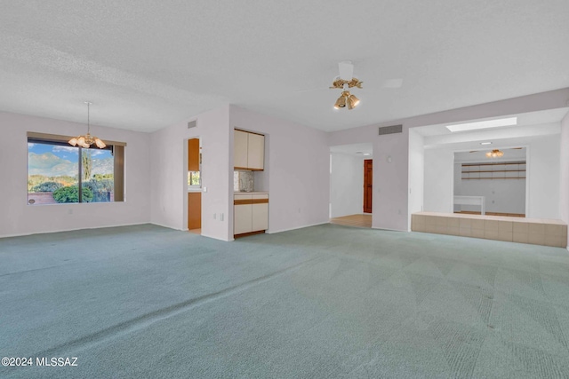 unfurnished living room featuring carpet flooring, ceiling fan with notable chandelier, and a textured ceiling