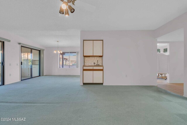 living room with a textured ceiling, light colored carpet, and a notable chandelier