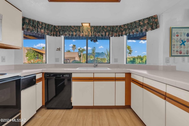 kitchen featuring black dishwasher, white cabinetry, and sink