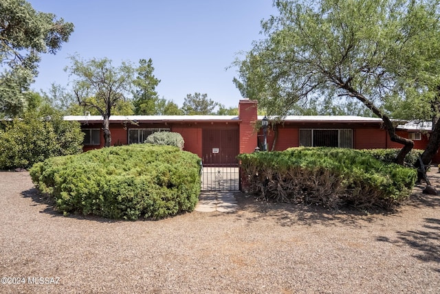 ranch-style home with a gate and a chimney