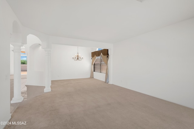 empty room featuring light carpet, an inviting chandelier, and decorative columns