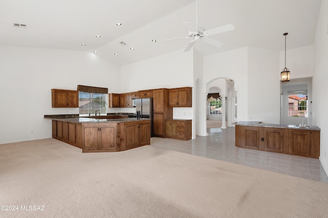 kitchen with kitchen peninsula, high vaulted ceiling, decorative light fixtures, and light colored carpet