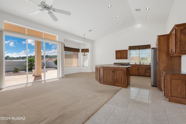 kitchen with a kitchen island, lofted ceiling, light carpet, stainless steel refrigerator, and decorative light fixtures