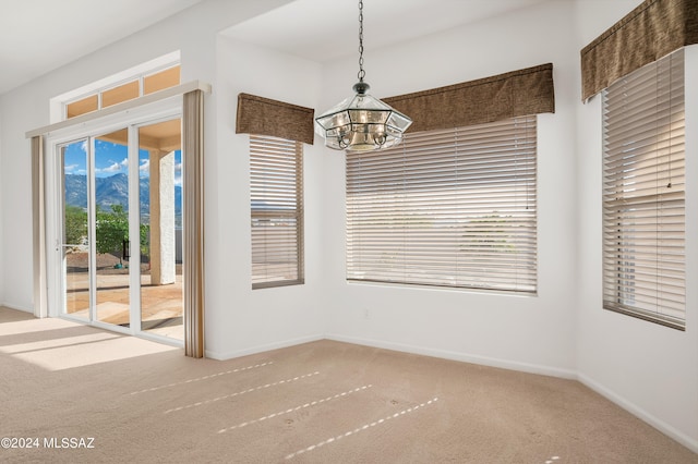 unfurnished dining area featuring a notable chandelier, plenty of natural light, and carpet