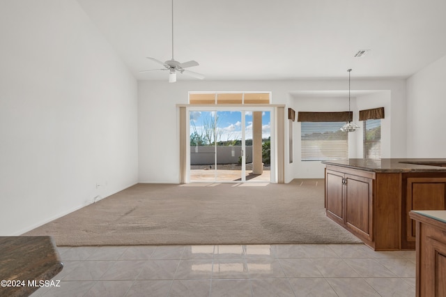 unfurnished living room featuring light carpet, ceiling fan with notable chandelier, and vaulted ceiling