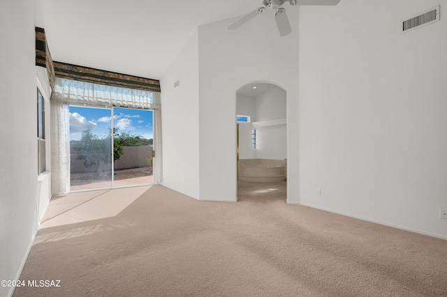 empty room featuring light colored carpet, a high ceiling, and ceiling fan