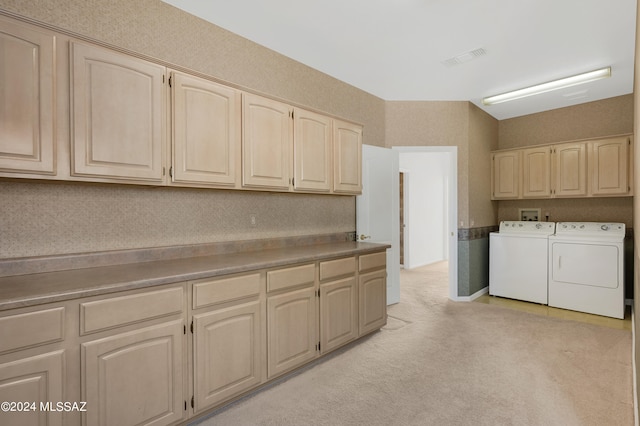 laundry area featuring light colored carpet, washer and clothes dryer, and cabinets