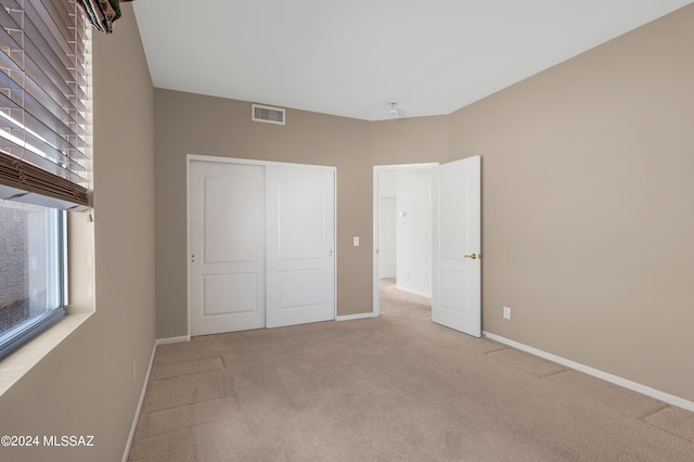 unfurnished bedroom featuring light carpet and a closet