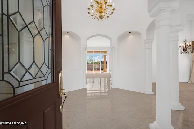 entryway with decorative columns, light tile patterned floors, and a chandelier