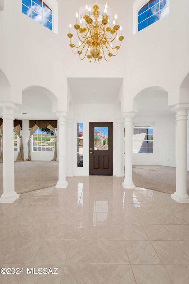 entrance foyer with a towering ceiling, light colored carpet, and an inviting chandelier