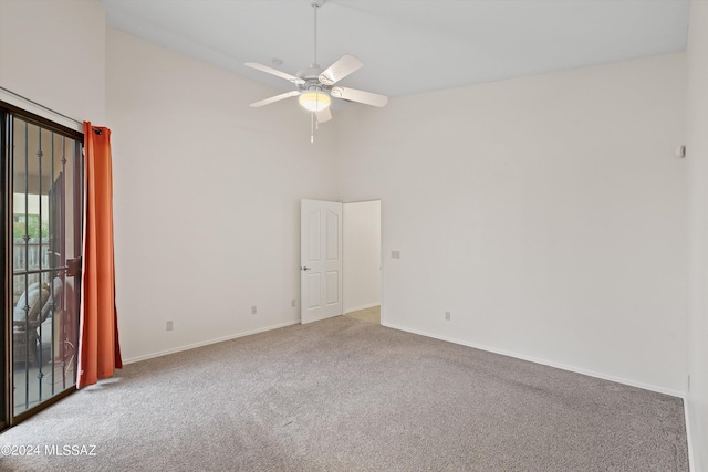 carpeted empty room featuring high vaulted ceiling and ceiling fan