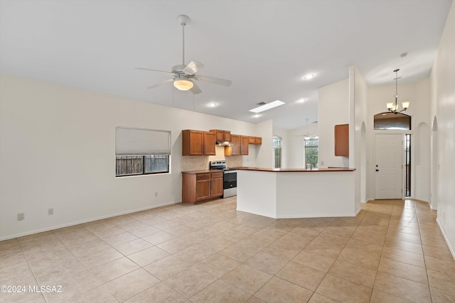 kitchen featuring stainless steel electric range oven, light tile patterned floors, ceiling fan with notable chandelier, and kitchen peninsula