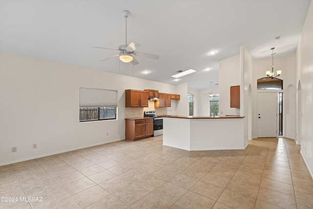 kitchen featuring stainless steel electric range, hanging light fixtures, vaulted ceiling, light tile patterned floors, and ceiling fan with notable chandelier