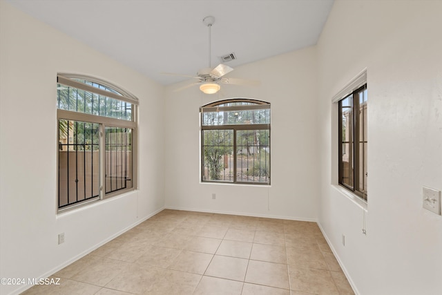 tiled empty room with ceiling fan and plenty of natural light