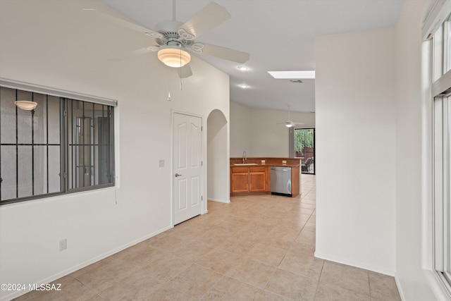 tiled spare room featuring sink, a skylight, and ceiling fan