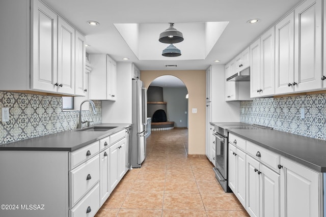 kitchen with sink, backsplash, white cabinetry, light tile patterned floors, and stainless steel appliances