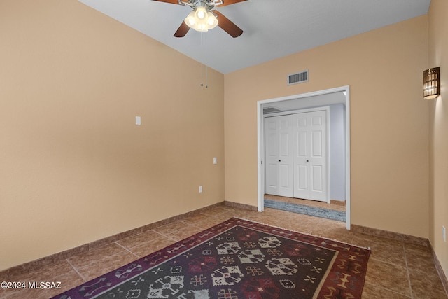 tiled bedroom with ceiling fan and a closet