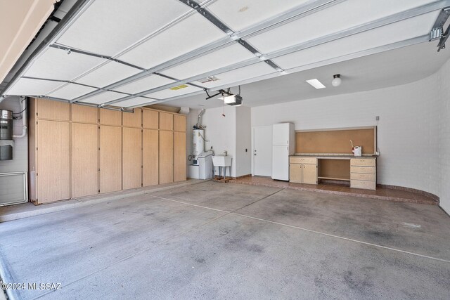 garage with sink, gas water heater, white fridge, and a garage door opener