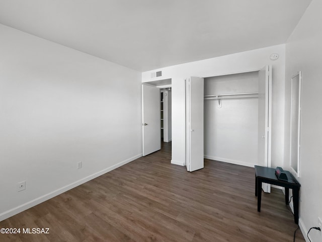 unfurnished bedroom with dark wood-type flooring and a closet