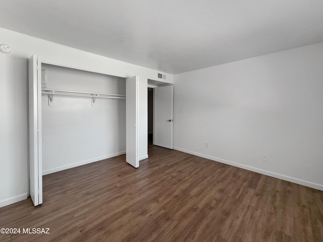 unfurnished bedroom with a closet and dark hardwood / wood-style floors