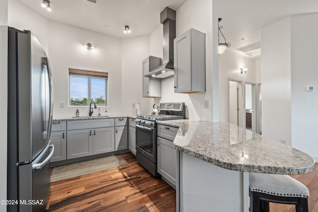 kitchen with wall chimney range hood, dark hardwood / wood-style floors, range with gas stovetop, sink, and stainless steel fridge