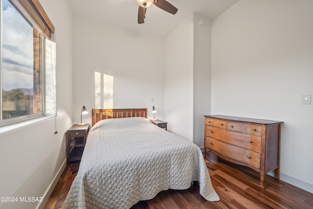 bedroom featuring ceiling fan, dark wood-type flooring, and multiple windows