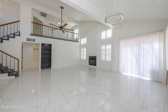 unfurnished living room featuring a towering ceiling and ceiling fan