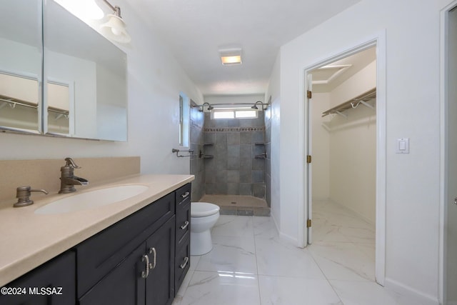 bathroom with a tile shower, vanity, and toilet