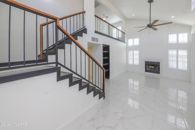 staircase featuring ceiling fan, a towering ceiling, and beam ceiling