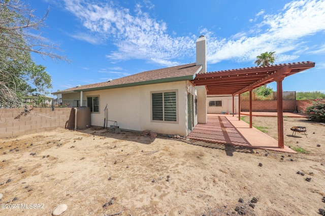 rear view of property featuring a fire pit and a pergola