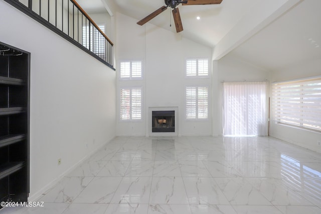 unfurnished living room with high vaulted ceiling, beam ceiling, ceiling fan, and plenty of natural light