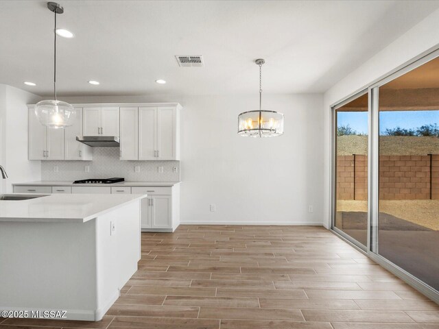 350 N Pecan Canyon Ln, Sahuarita, AZ 85629 - kitchen featuring gas cooktop, under cabinet range hood, a sink, light wood-style floors, and a chandelier