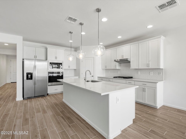 350 N Pecan Canyon Ln, Sahuarita, AZ 85629 - kitchen with stainless steel appliances, a sink, light wood-type flooring, white cabinetry, and under cabinet range hood