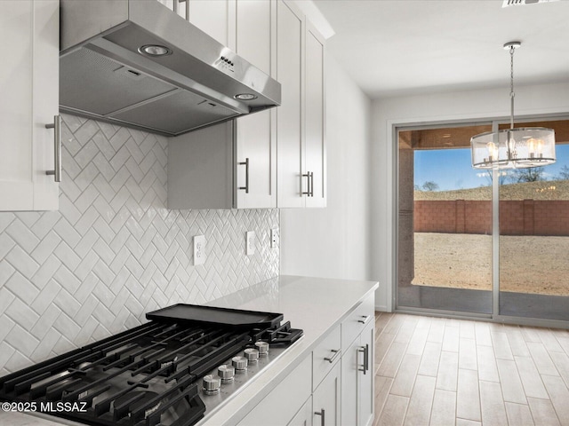 350 N Pecan Canyon Ln, Sahuarita, AZ 85629 - kitchen featuring exhaust hood, stainless steel gas cooktop, a chandelier, tasteful backsplash, and white cabinetry