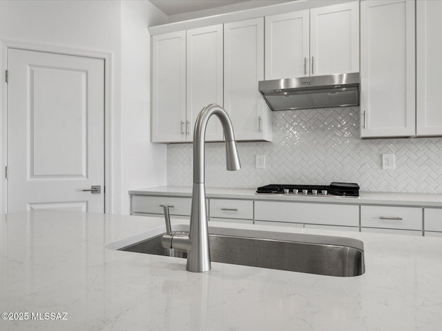 350 N Pecan Canyon Ln, Sahuarita, AZ 85629 - kitchen with under cabinet range hood, a sink, decorative backsplash, white cabinets, and light stone countertops
