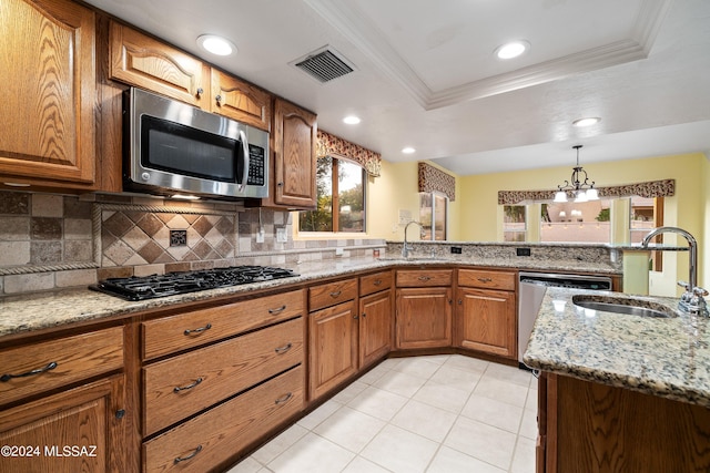 kitchen featuring light tile patterned flooring, light stone counters, a tray ceiling, stainless steel appliances, and decorative light fixtures