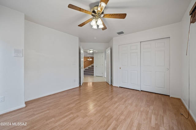 unfurnished bedroom featuring light wood-type flooring, ceiling fan, and a closet