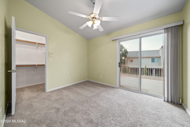 unfurnished bedroom with a spacious closet, access to exterior, lofted ceiling, carpet flooring, and ceiling fan