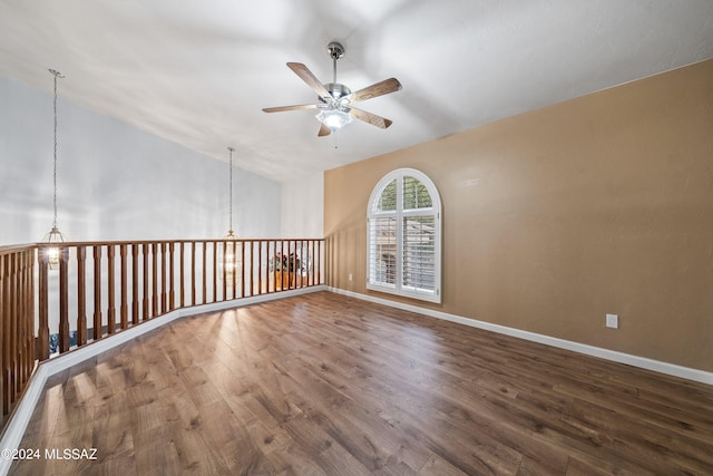 spare room featuring lofted ceiling, wood-type flooring, and ceiling fan with notable chandelier