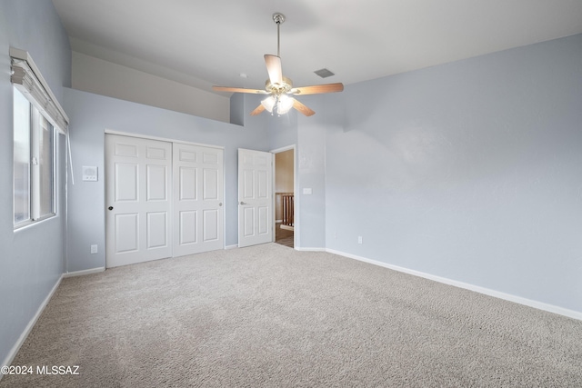 unfurnished bedroom featuring a closet, carpet floors, ceiling fan, and a high ceiling