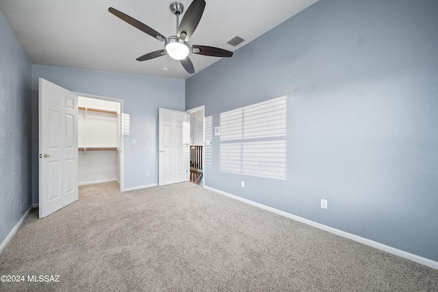 unfurnished bedroom featuring vaulted ceiling, a closet, carpet floors, and ceiling fan